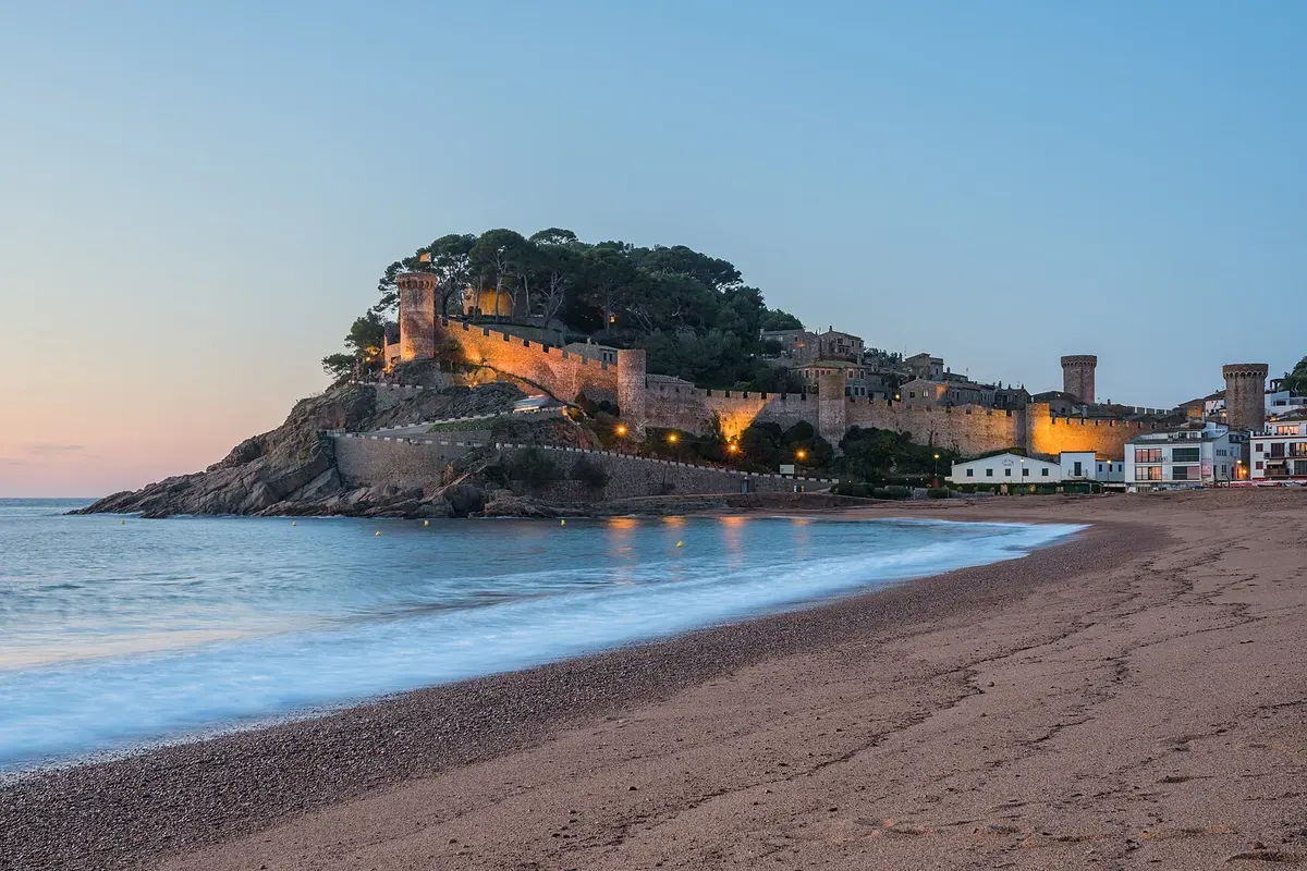 Middeleeuwse muren van de Vila Vella boven het strand van Tossa de Mar in de avondschemer, Costa Brava