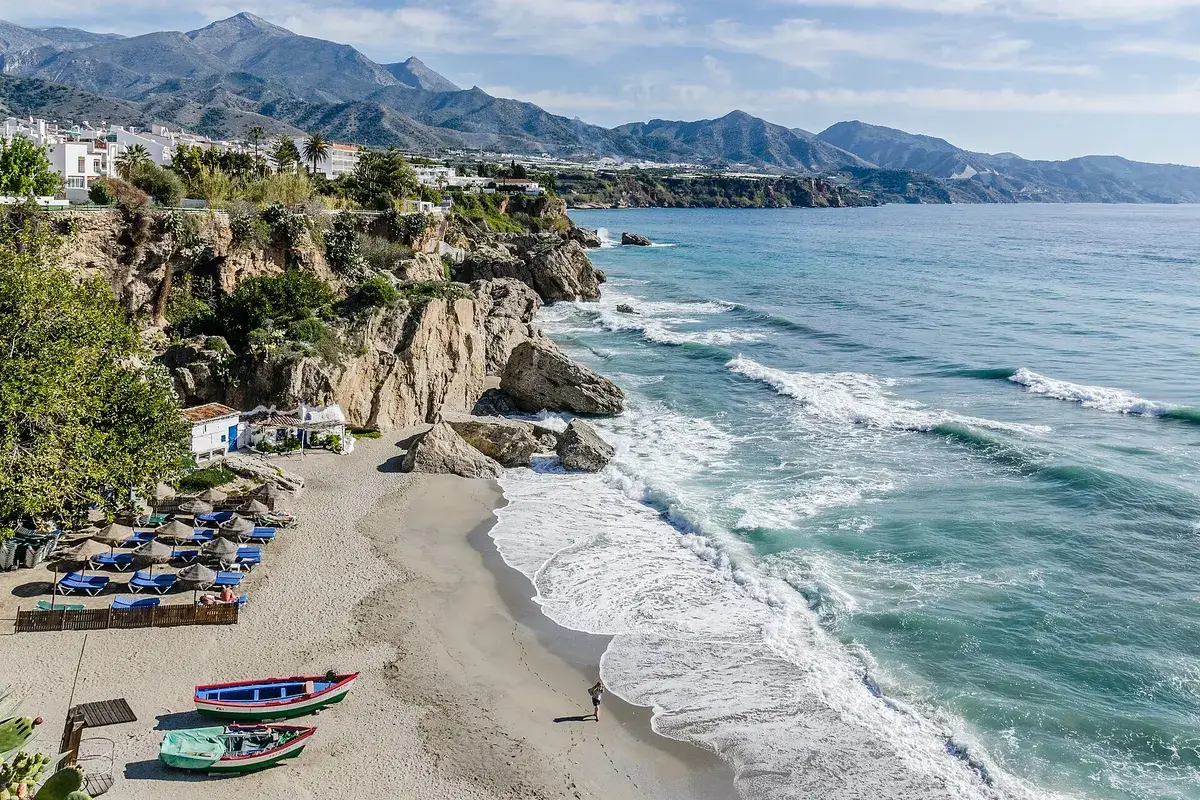 Uitzicht vanaf de Balcón de Europa in Nerja op een zandbaai met rotsen en de bergen erachter