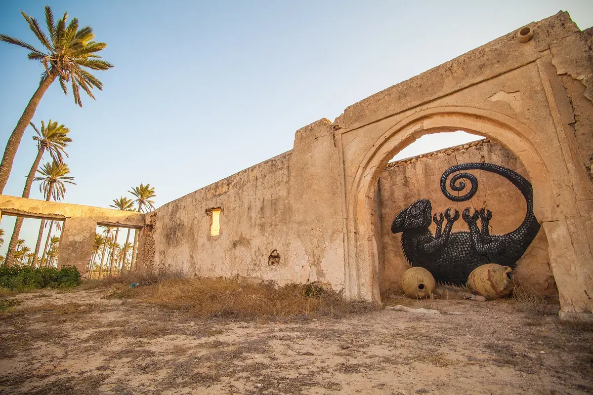 Muurschildering van een kameleon op een oude poort in Erriadh, het Djerbahood-dorp op Djerba