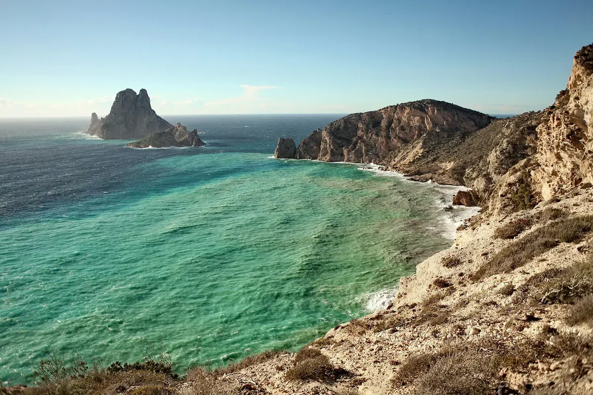 Turquoise zee bij Cala d'Hort met de rots Es Vedrà op de achtergrond, Ibiza