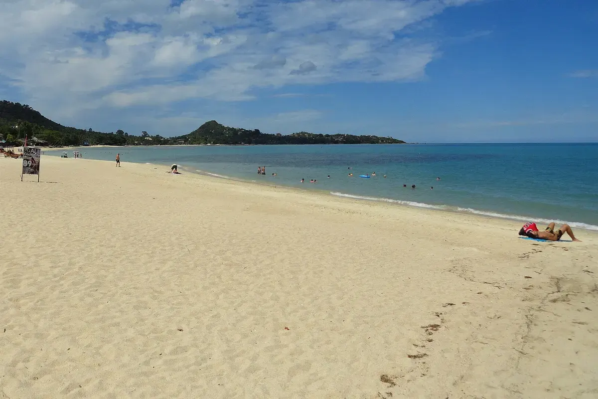 Breed zandstrand van Lamai aan de oostkust van Koh Samui met groene heuvels op de achtergrond