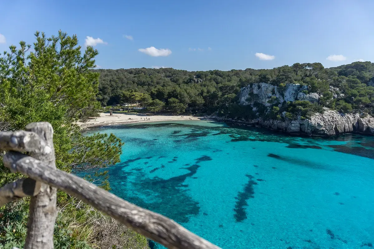 Turquoise water in de baai van Cala Macarella tussen dennenbossen en witte rotsen, Menorca