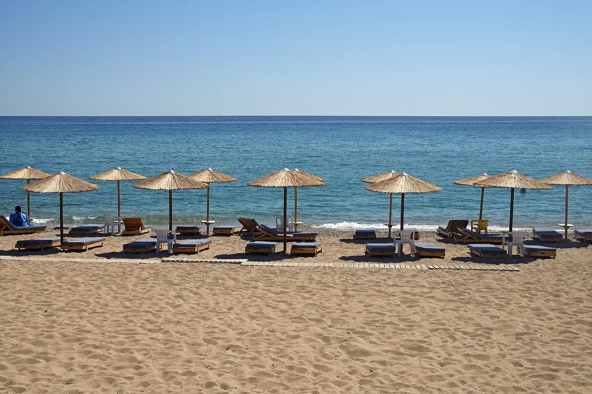Een rij rieten parasols op het zandstrand van Stegna aan de oostkust van Rhodos