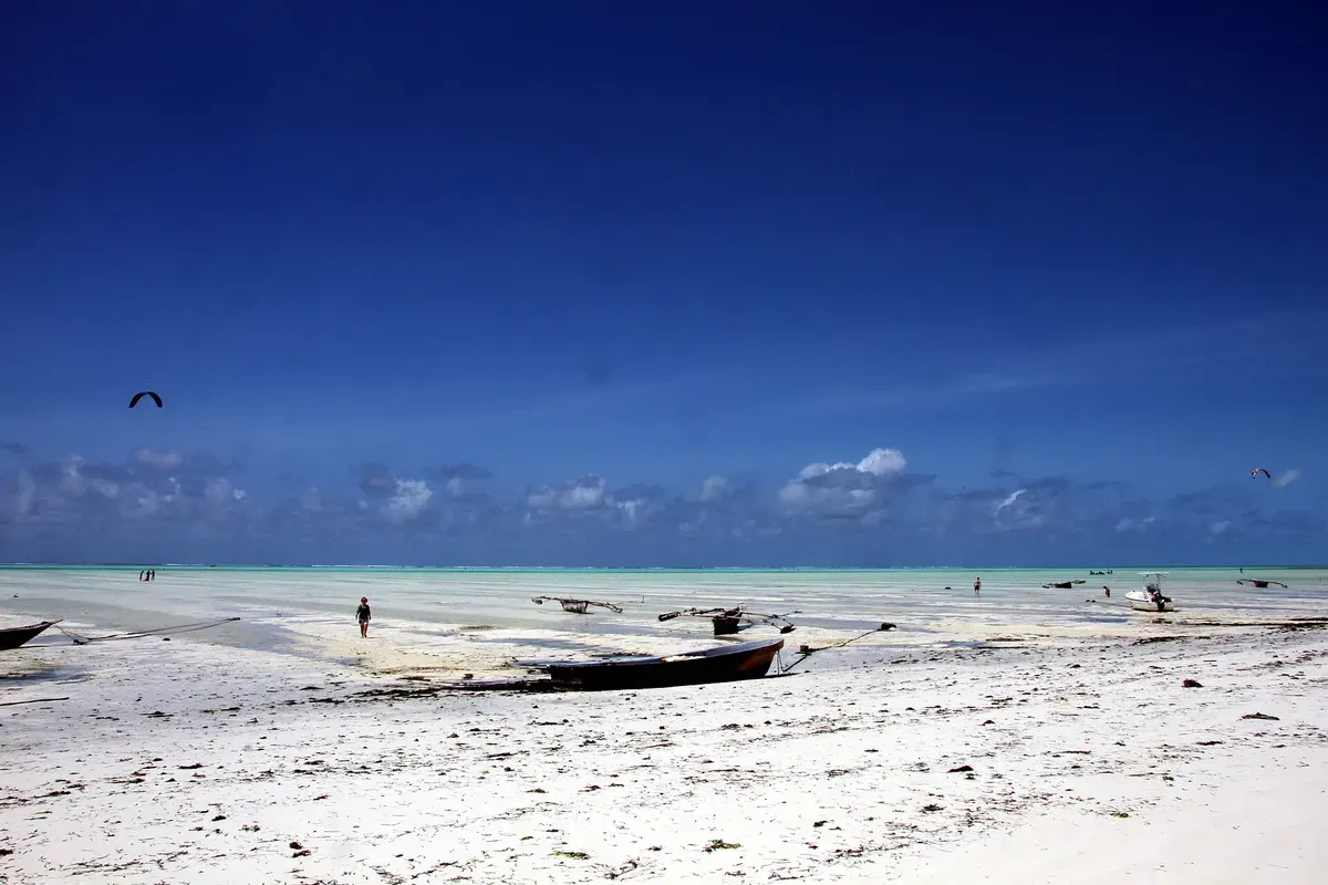 Wit strand en turquoise water bij Kite Beach op Sal, met kitesurfers in de verte